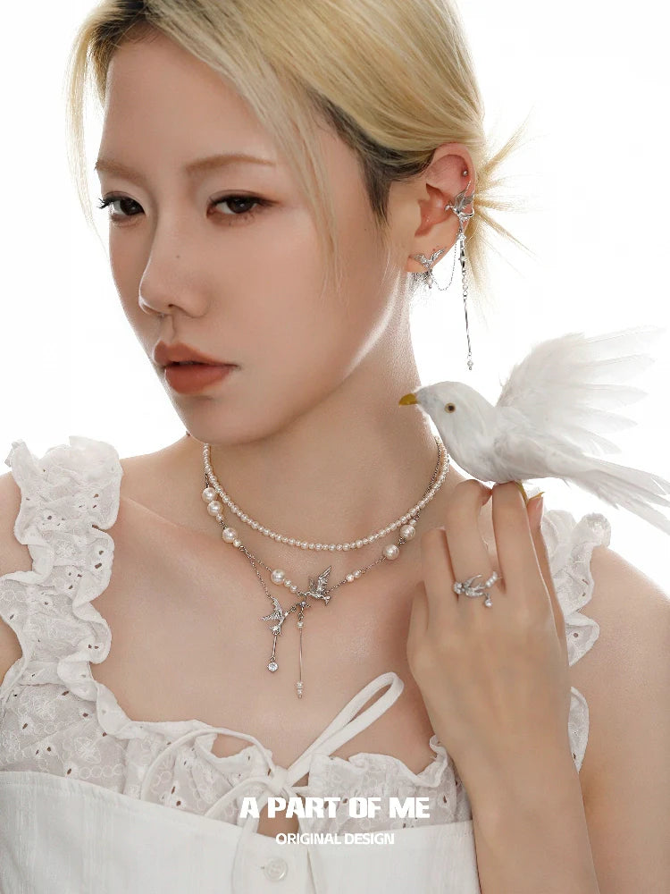 Elegant model wearing a silver pearl ring along with layered pearl jewelry and a bird accessory