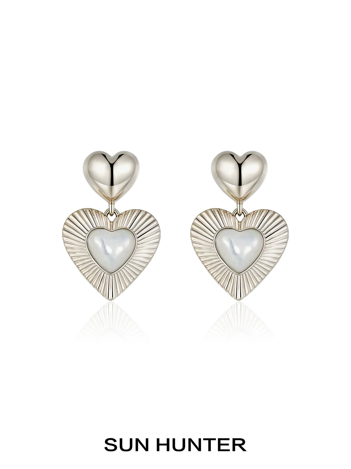 SUN HUNTER heart shaped statement earrings with a silver finish and sleek design