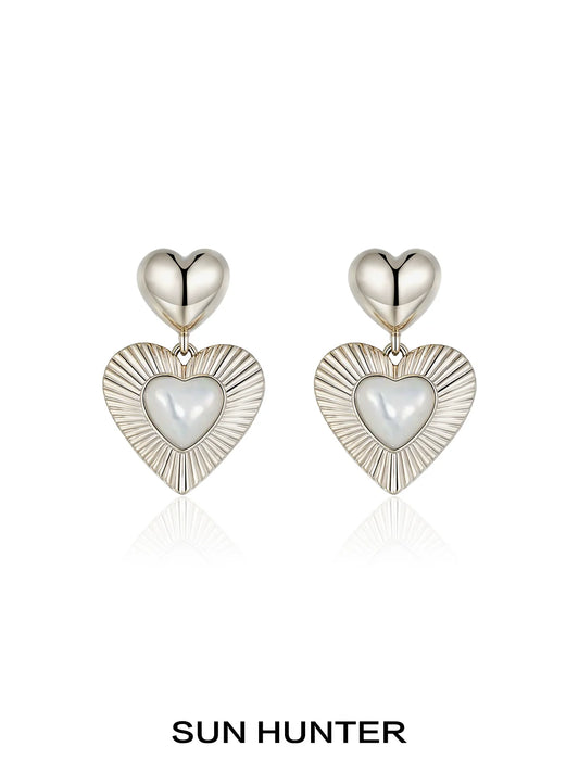 SUN HUNTER heart shaped statement earrings with a silver finish and sleek design