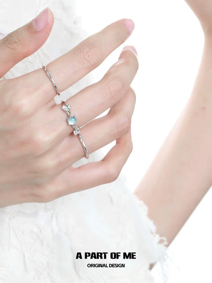 A part of me blue gemstone statement ring on a hand with silver stacking rings