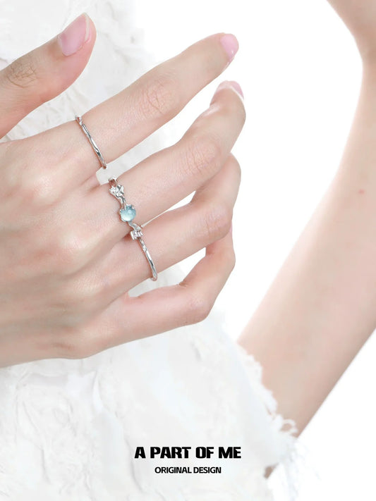 A part of me blue gemstone statement ring on a hand with silver stacking rings