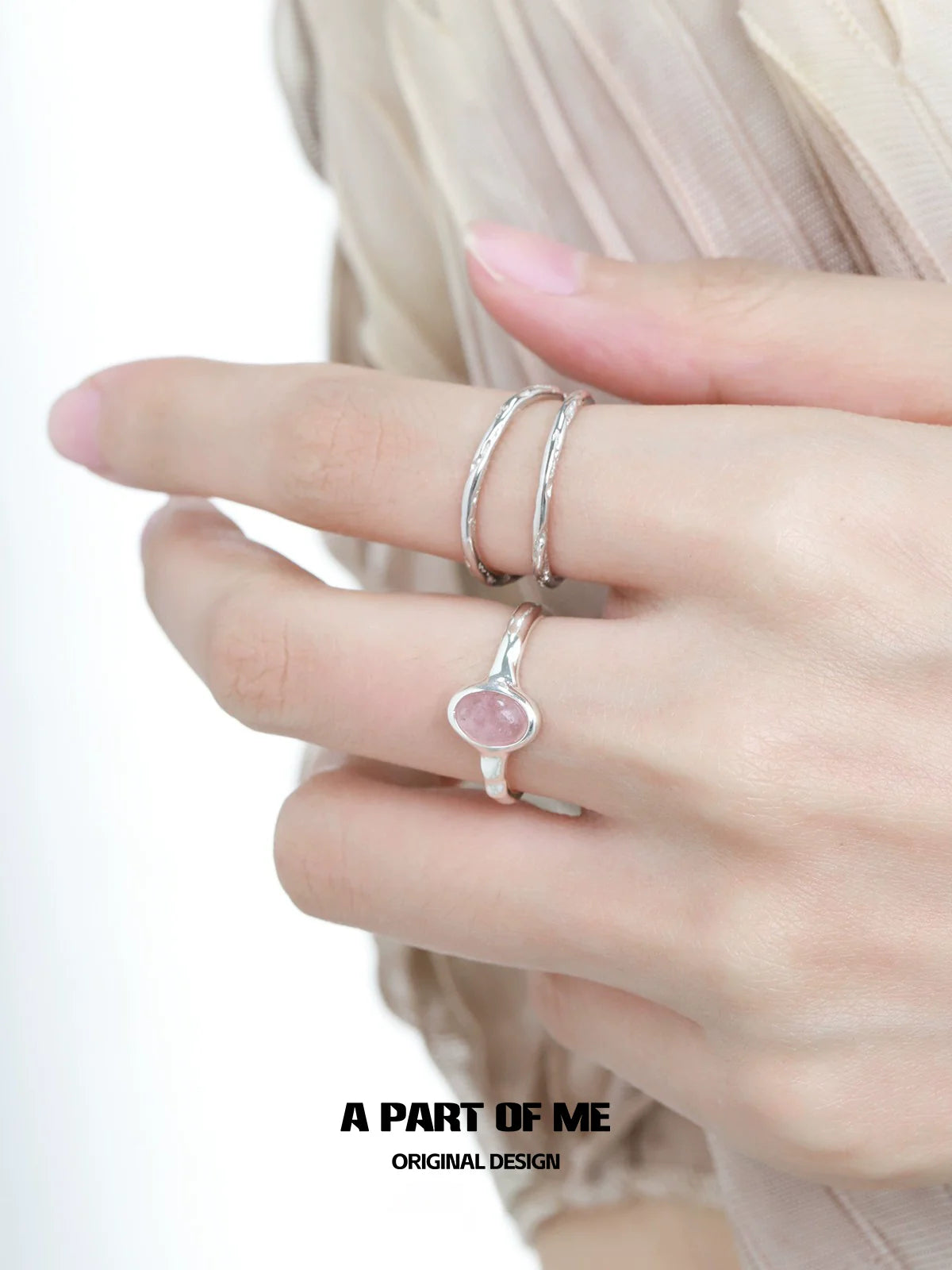 Elegant strawberry stone silver ring featured on a model's hand with delicate silver bands.
