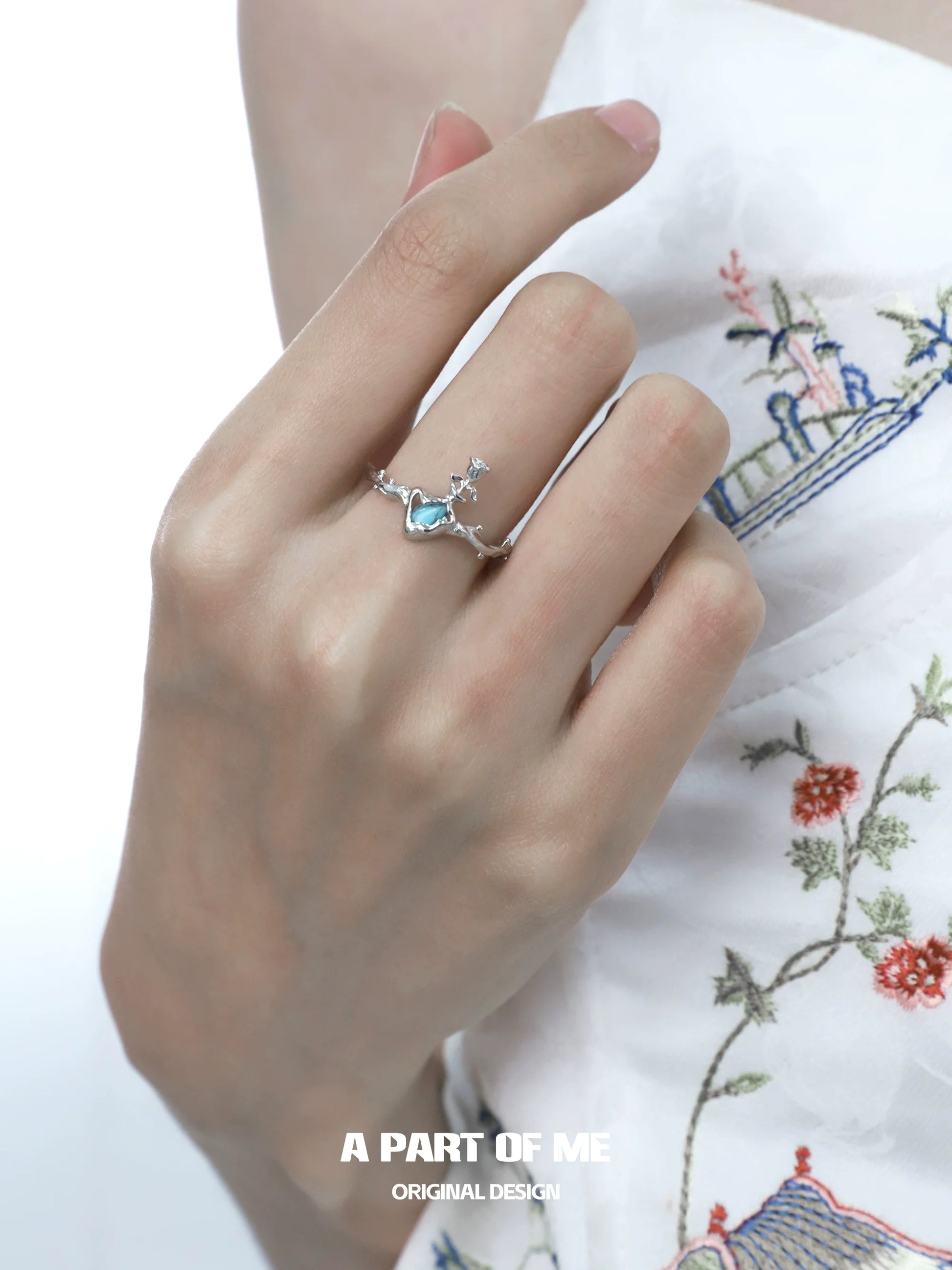 A PART OF ME delicate summer rose ring on a woman's hand with floral embroidery background