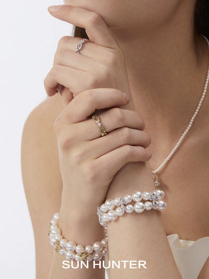 Elegant SUN HUNTER bow lace ring displayed on a model's hand with pearl bracelets
