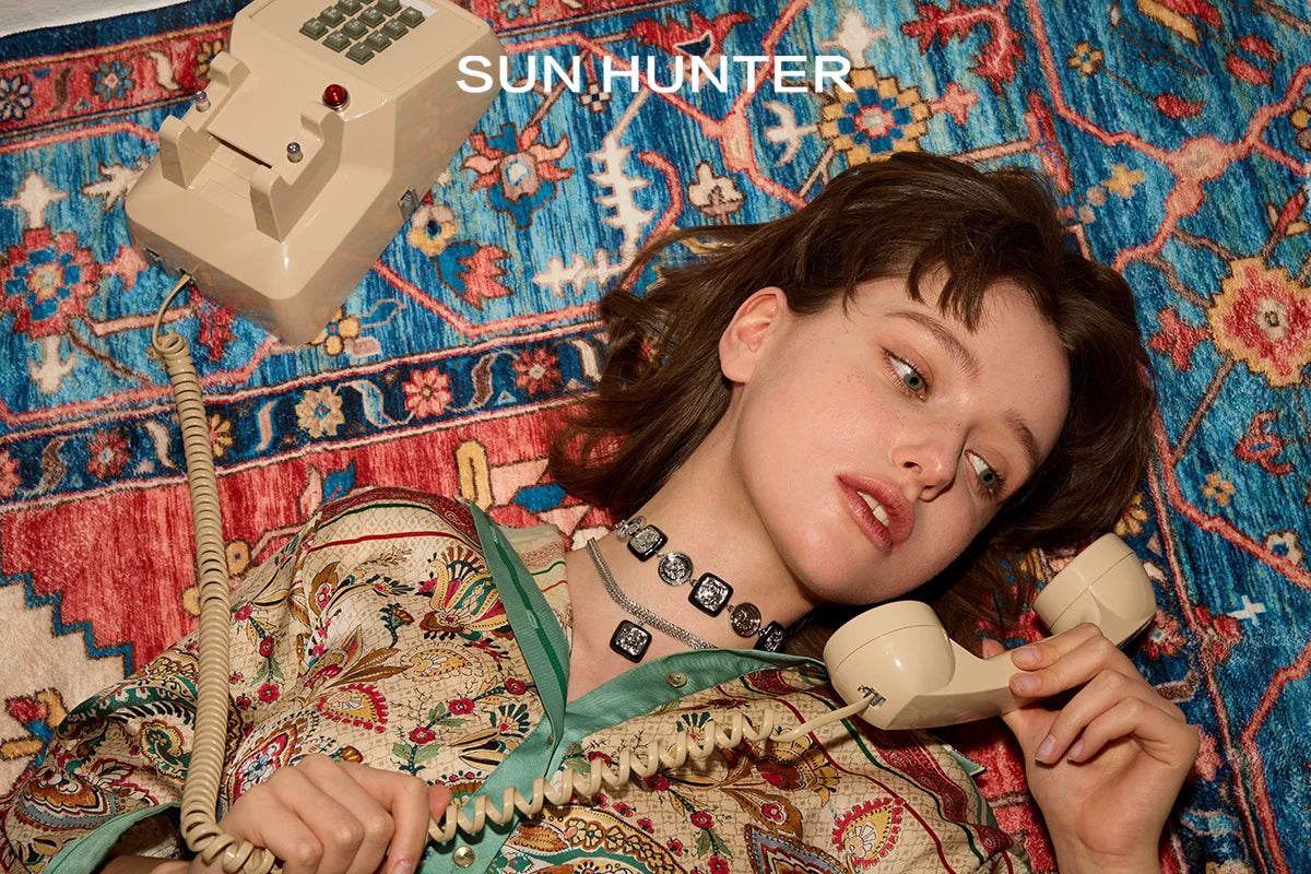 Woman wearing Sun Hunter Jewelry Planet Silver Necklace for Women while talking on a vintage phone