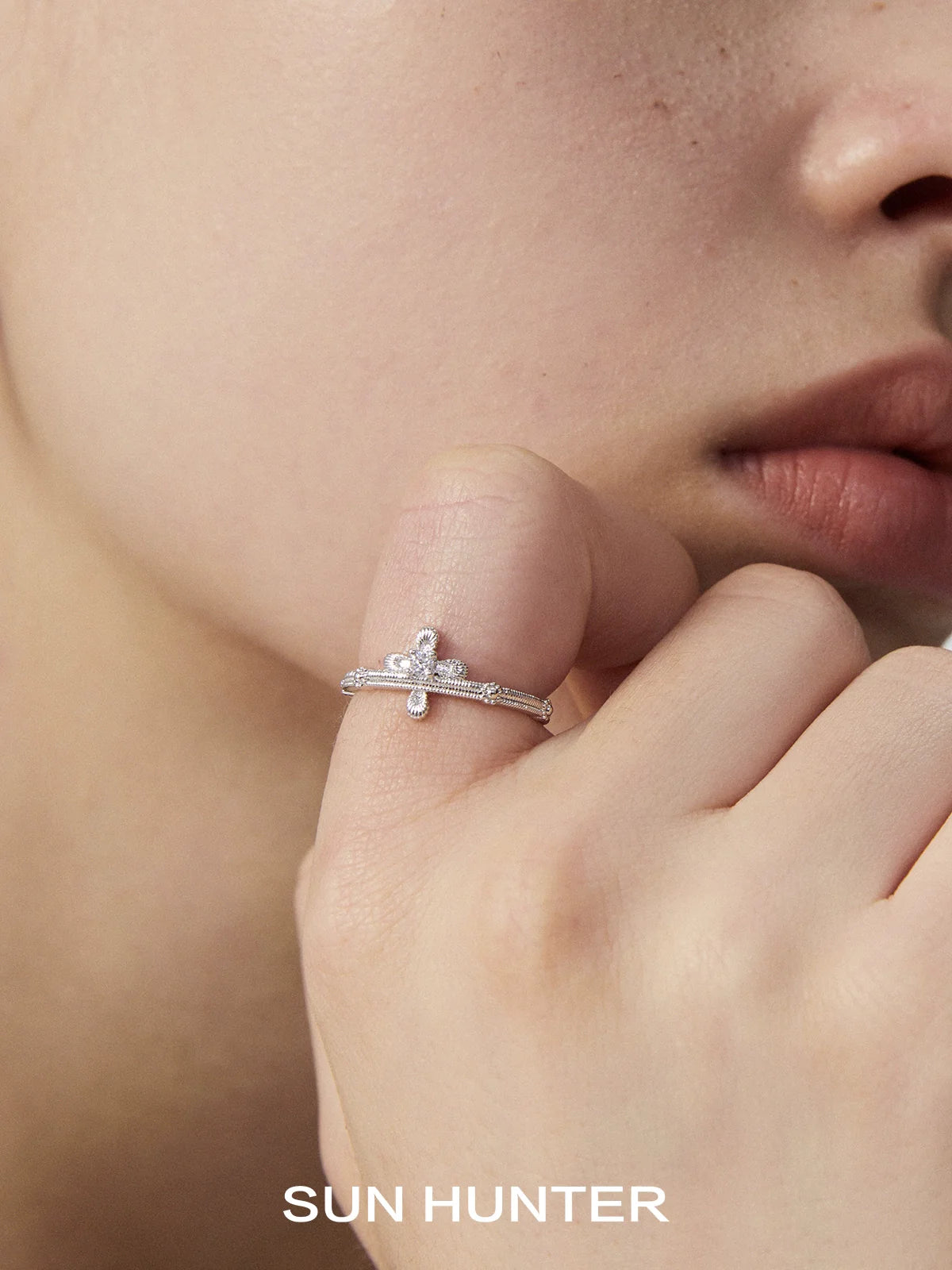 SUN HUNTER lace cross ring in sterling silver worn on a model's finger close to the face