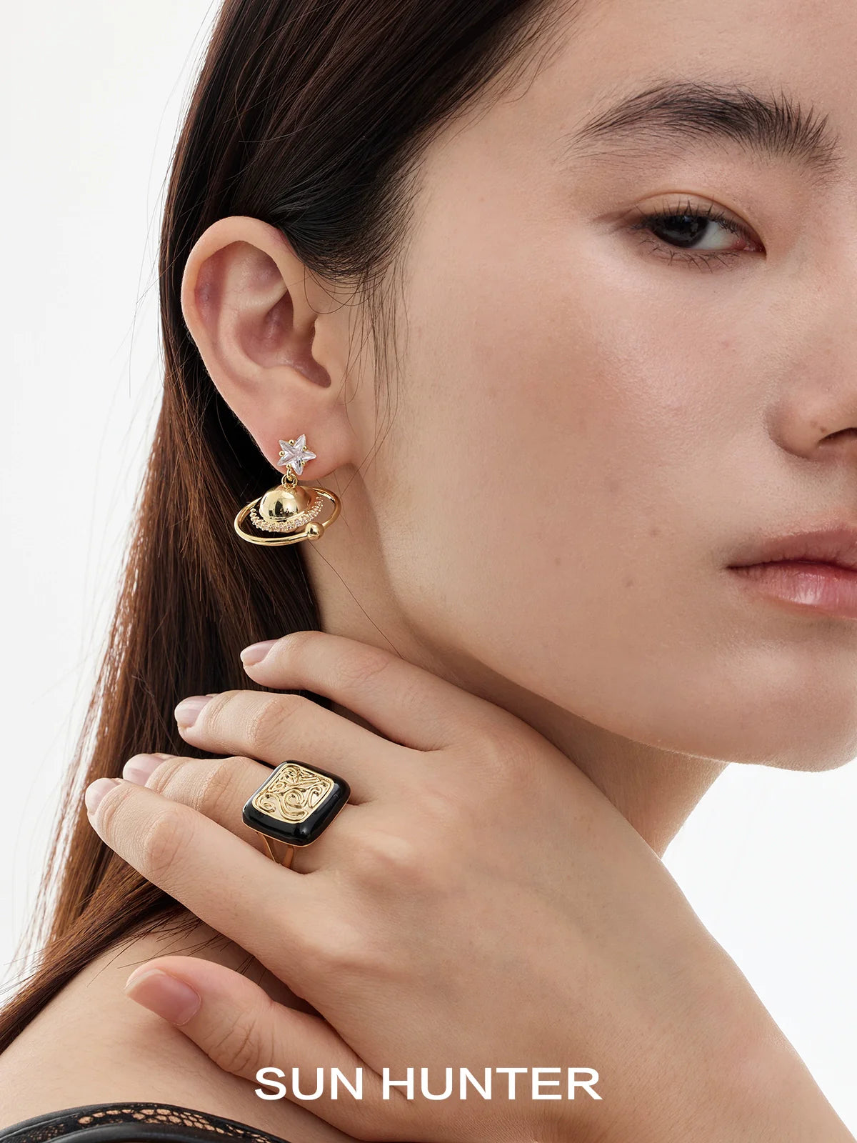 Model wearing SUN HUNTER retro coin ring with gold earrings featuring a planet design