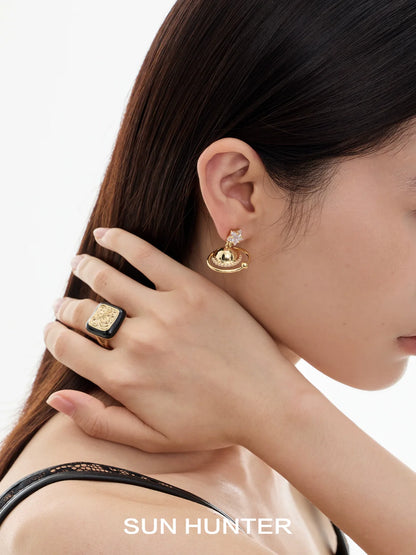 Woman wearing a retro coin ring and unique gold earrings from SUN HUNTER collection
