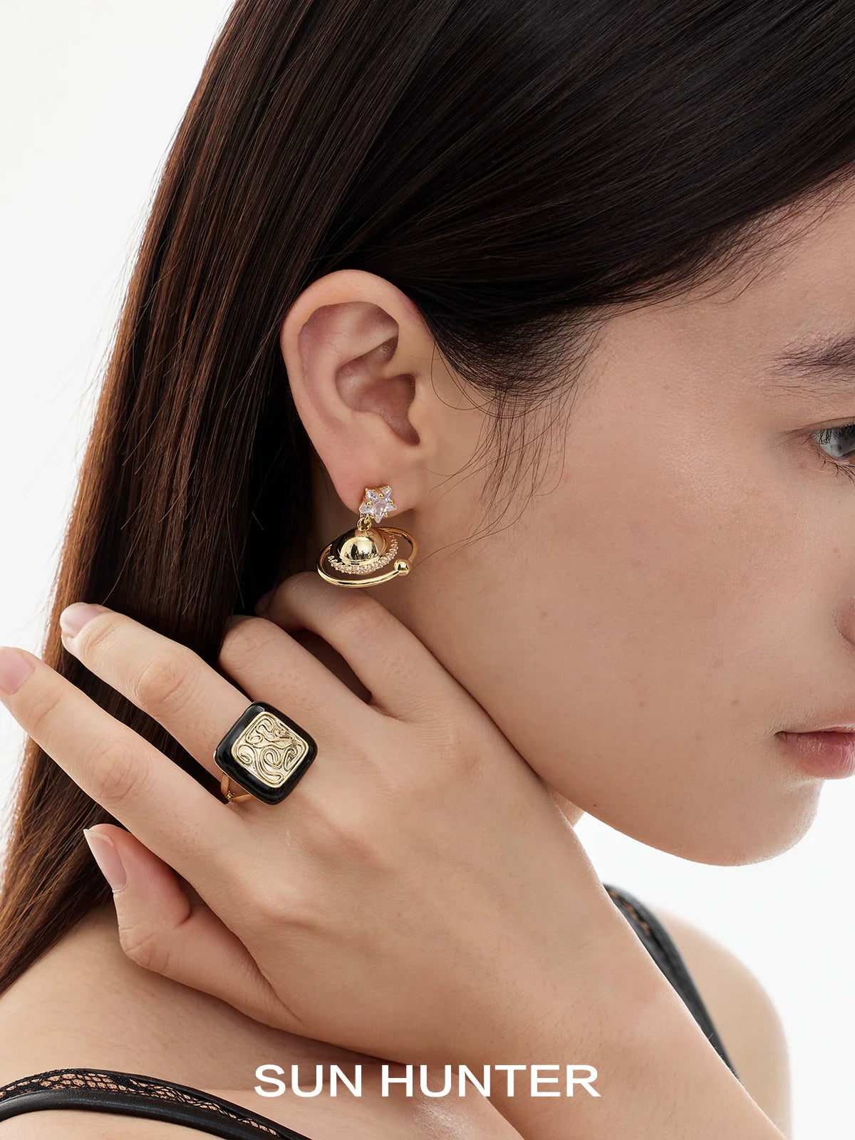 Woman wearing a vintage-inspired SUN HUNTER retro coin ring on her hand with elegant earrings