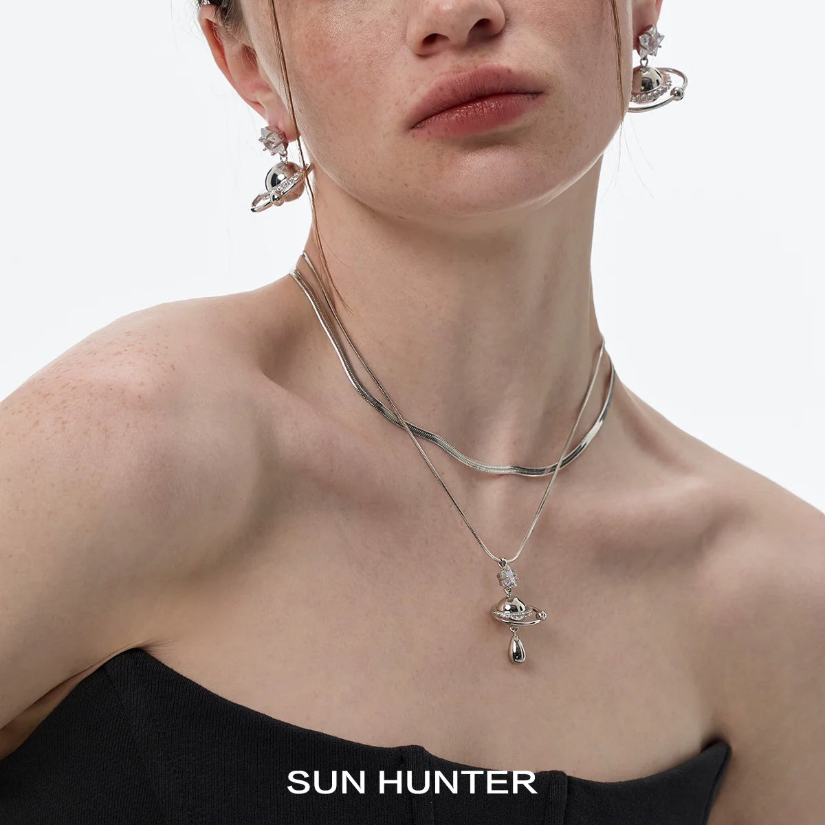SUN HUNTER universe planet silver necklace showcased on model's neck with matching earrings