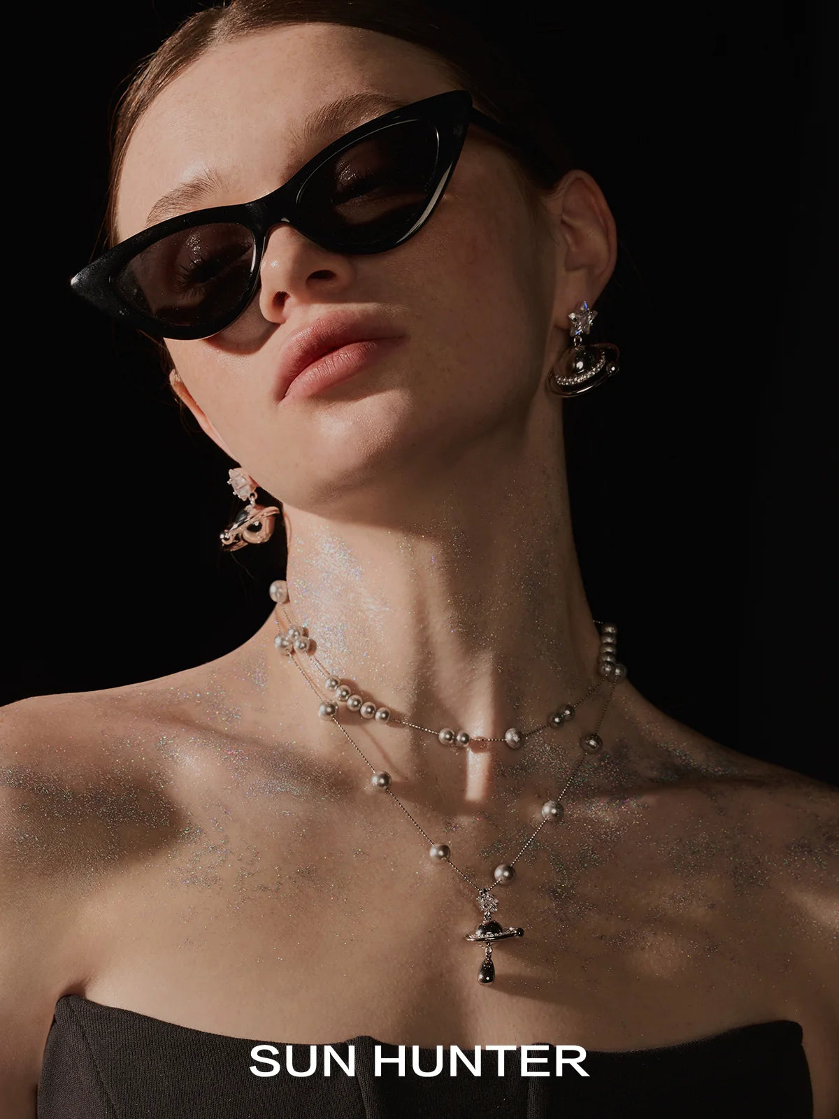 Elegant model wearing a SUN HUNTER universe planet silver necklace with intricate detailing and pearls