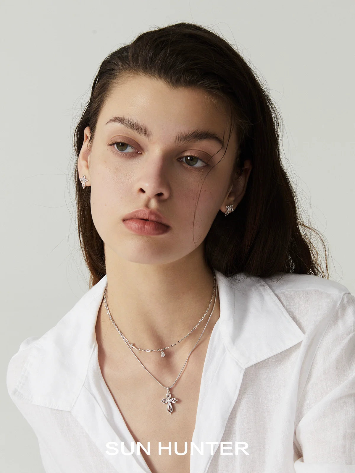 Elegant model wearing a teardrop cross necklace from SUN HUNTER, styled with a white shirt