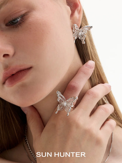 Elegant SUN HUNTER transparent butterfly earrings showcased on model's ear and hand