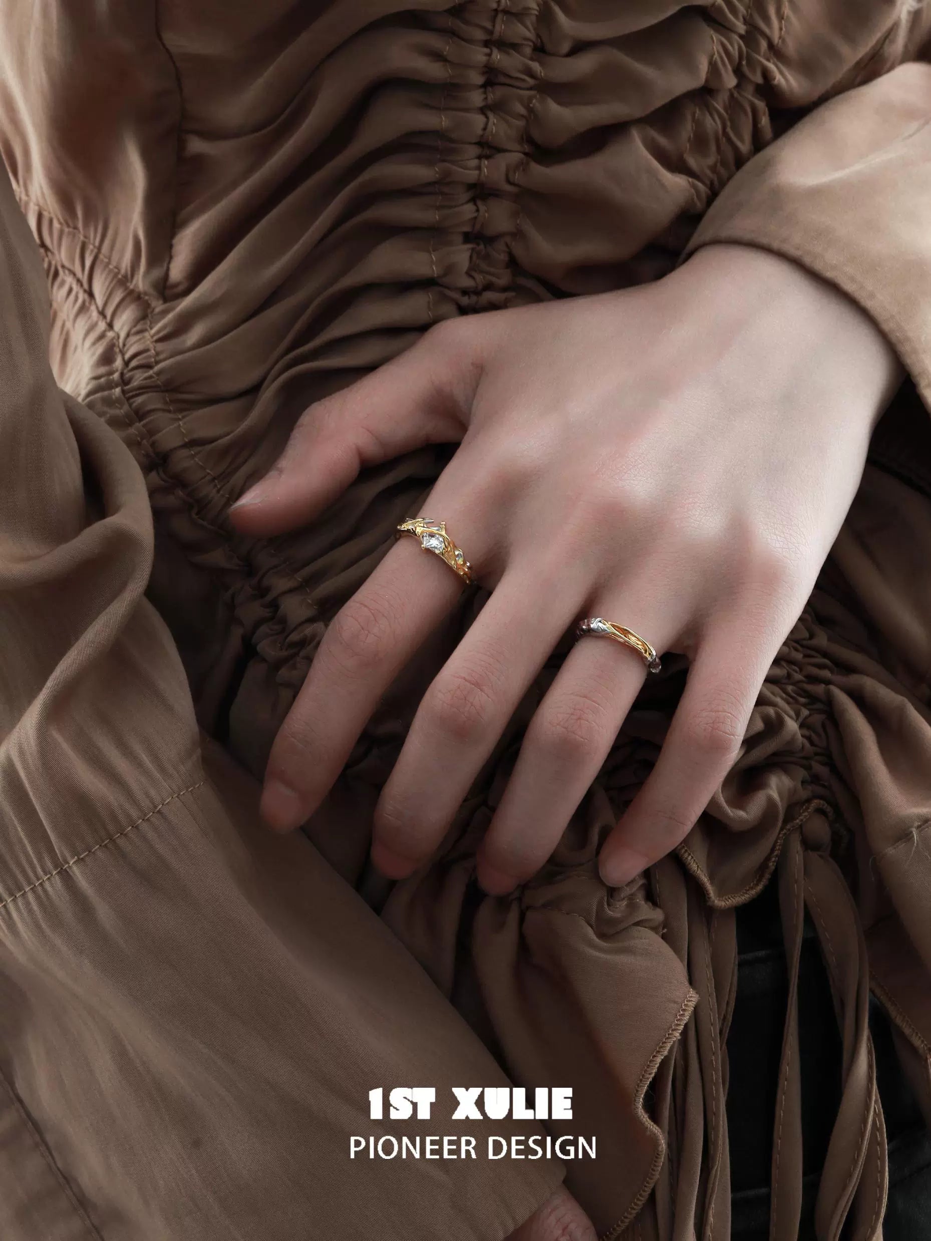 Elegant unique couple rings in gold, showcasing a stylish design on a hand against a textured fabric