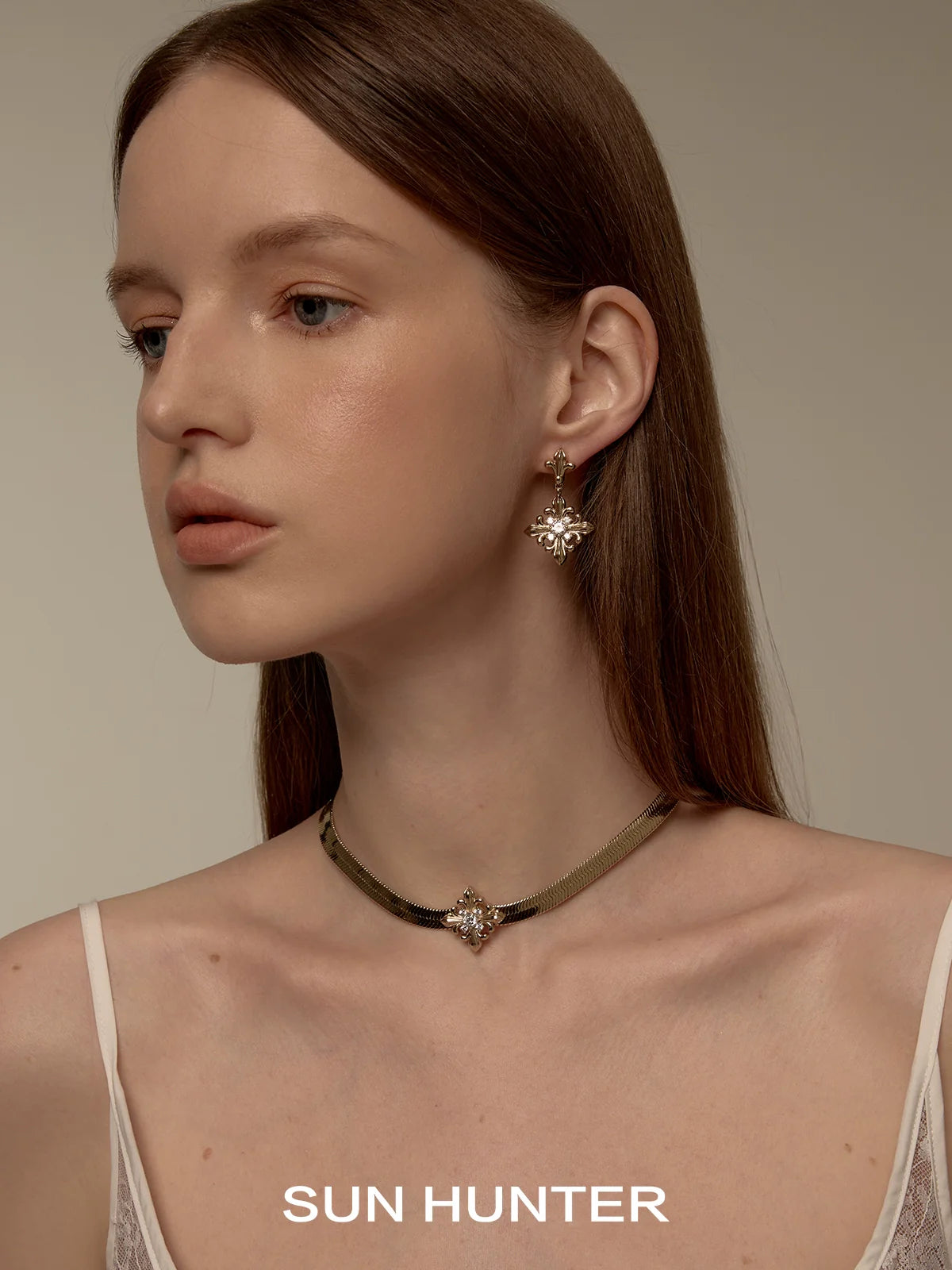 Elegant model wearing unique floral drop earrings by SUN HUNTER, showcasing intricate design and sparkle