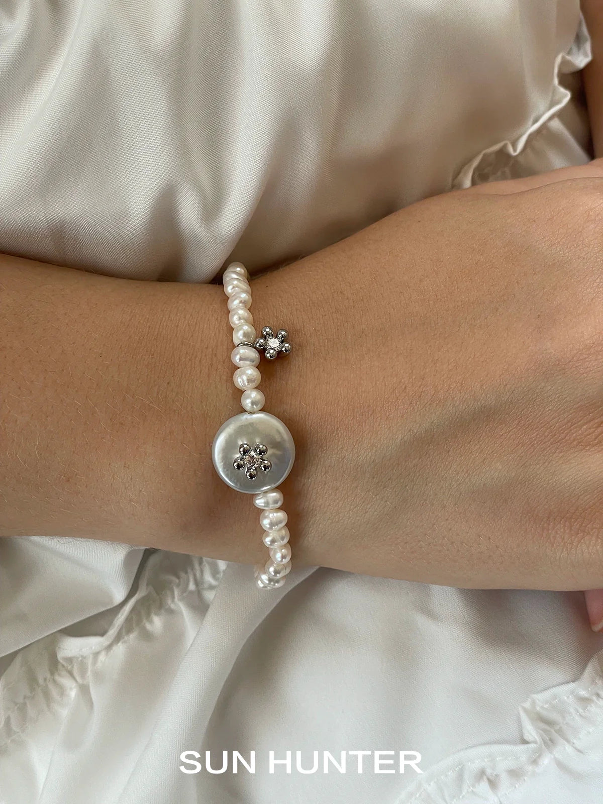 Elegant SUN HUNTER unique pearl bracelet featuring a decorative button and pearl accents