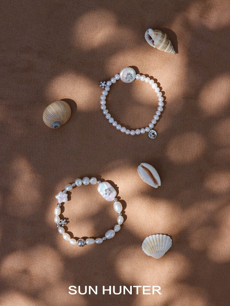 Two unique pearl bracelets by SUN HUNTER displayed with seashells for a beach-inspired look