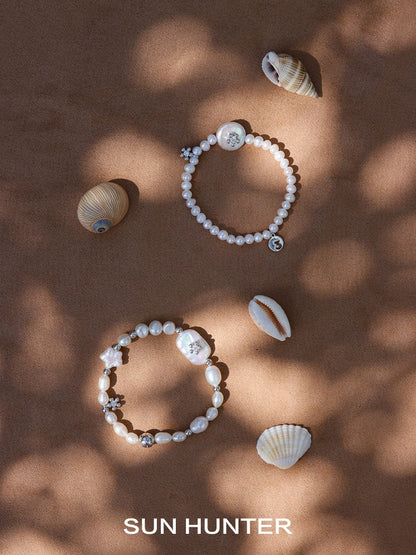 Two unique pearl bracelets by SUN HUNTER displayed with seashells for a beach-inspired look