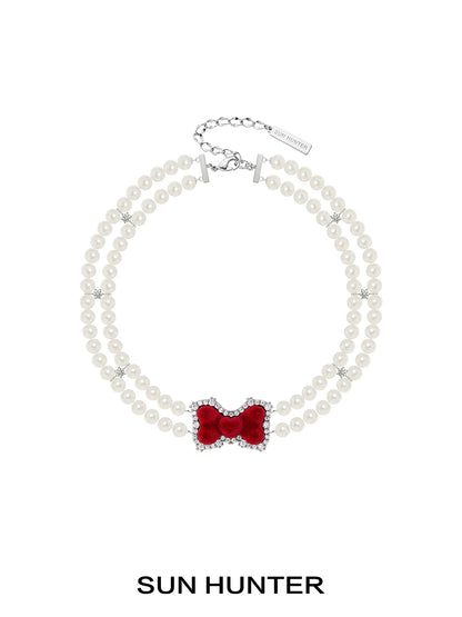 Elegant SUN HUNTER velvet bow pearl bracelet featuring a red bow and pearl beads