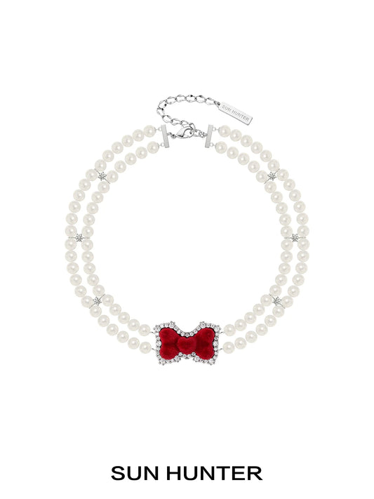 Elegant SUN HUNTER velvet bow pearl bracelet featuring a red bow and pearl beads