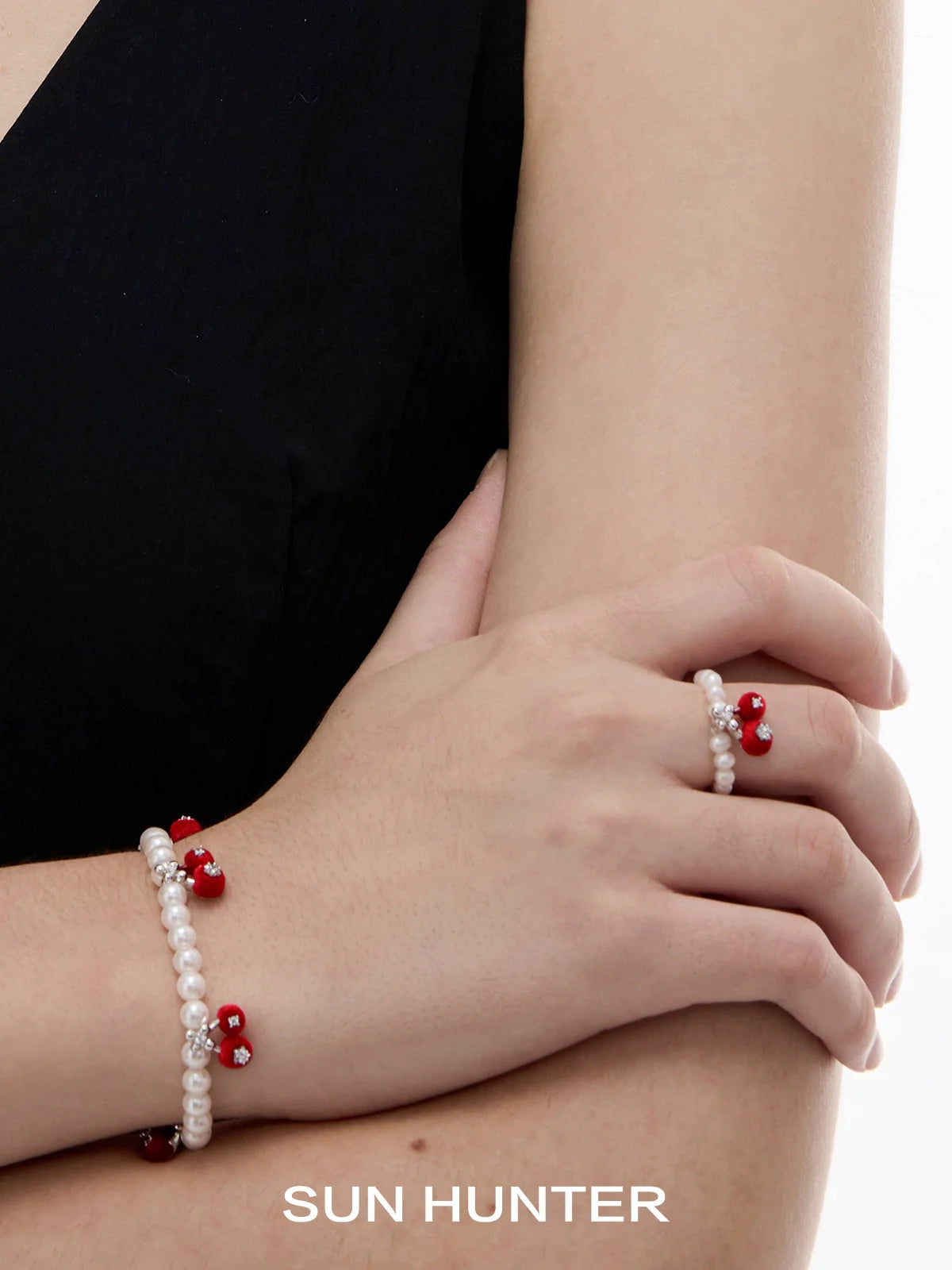 SUN HUNTER velvet cherry pearl ring paired with matching pearl bracelets on a model's hand