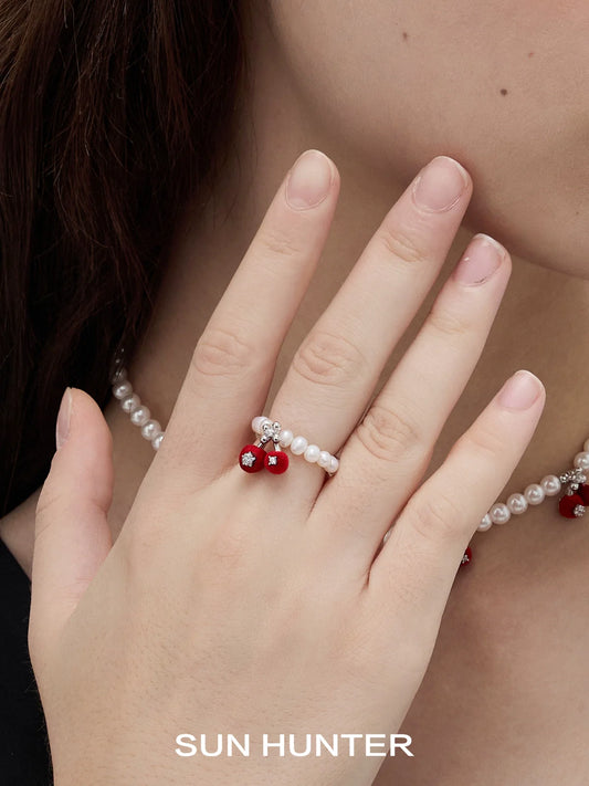Elegant SUN HUNTER velvet cherry pearl ring with red cherries and pearl accents on a model's hand