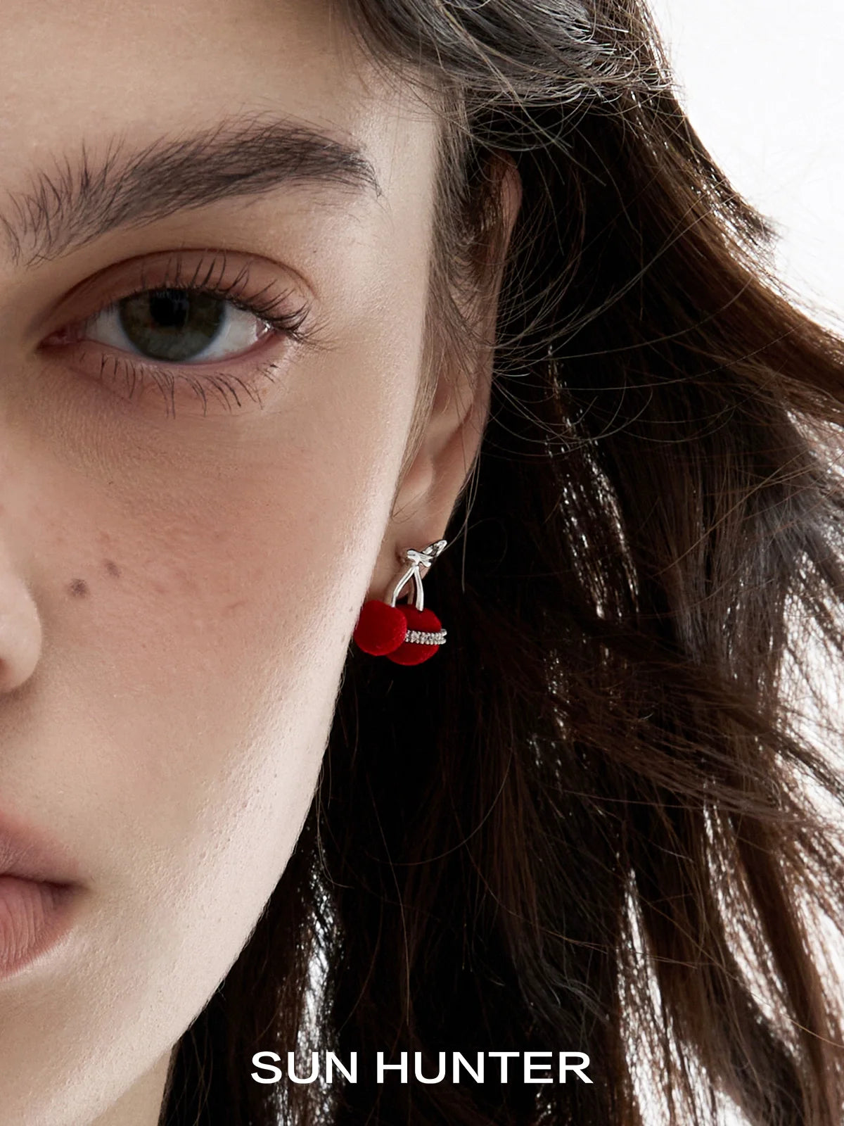 Close-up of a model wearing SUN HUNTER velvet cherry stud earrings for a stylish look