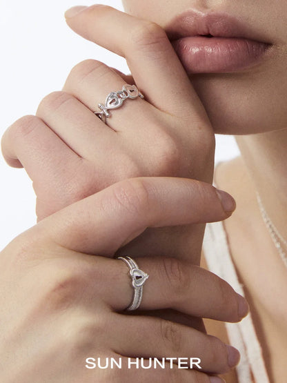 Two elegant silver rings featuring a love lock chain ring design displayed on model's hands