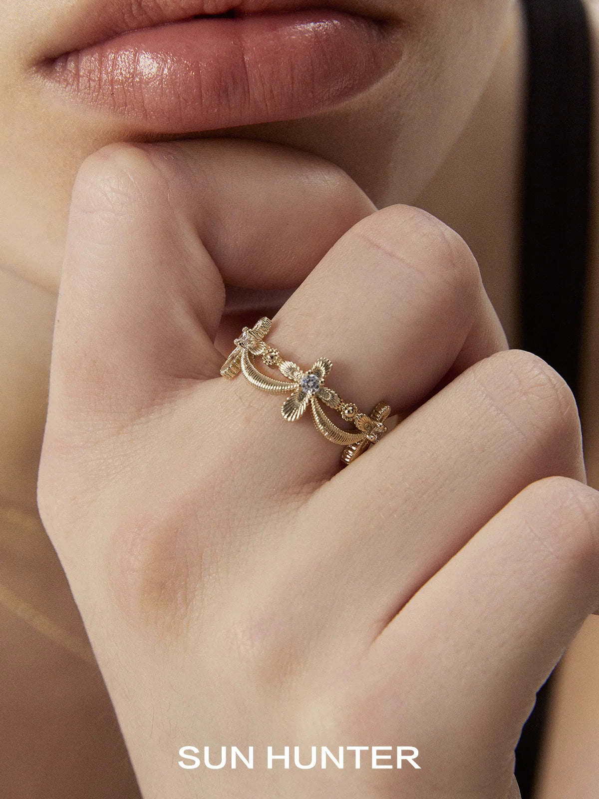 Elegant SUN HUNTER shimmer cross ring with intricate design worn on a model's finger