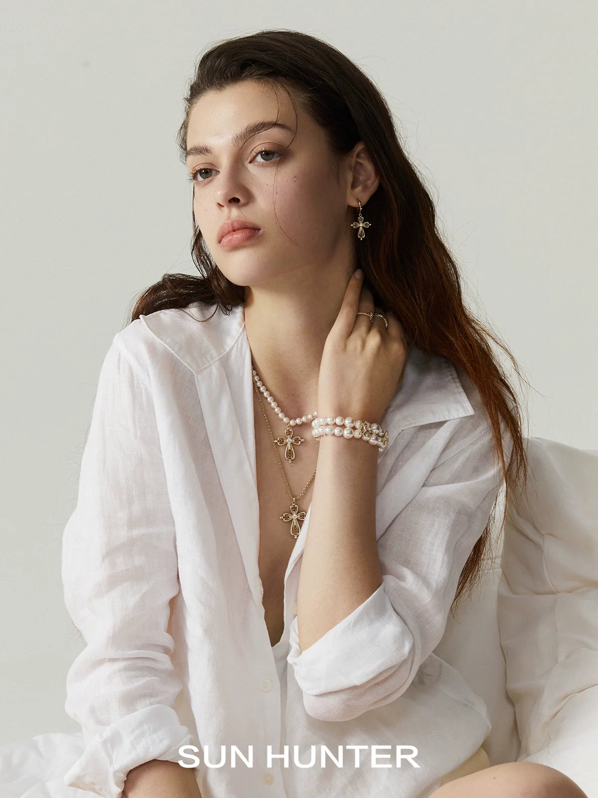 Model wearing SUN HUNTER shimmer cross ring alongside stylish beaded jewelry