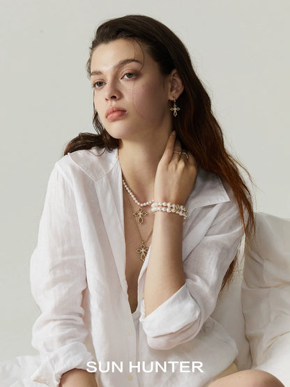 Model wearing SUN HUNTER shimmer cross ring alongside stylish beaded jewelry