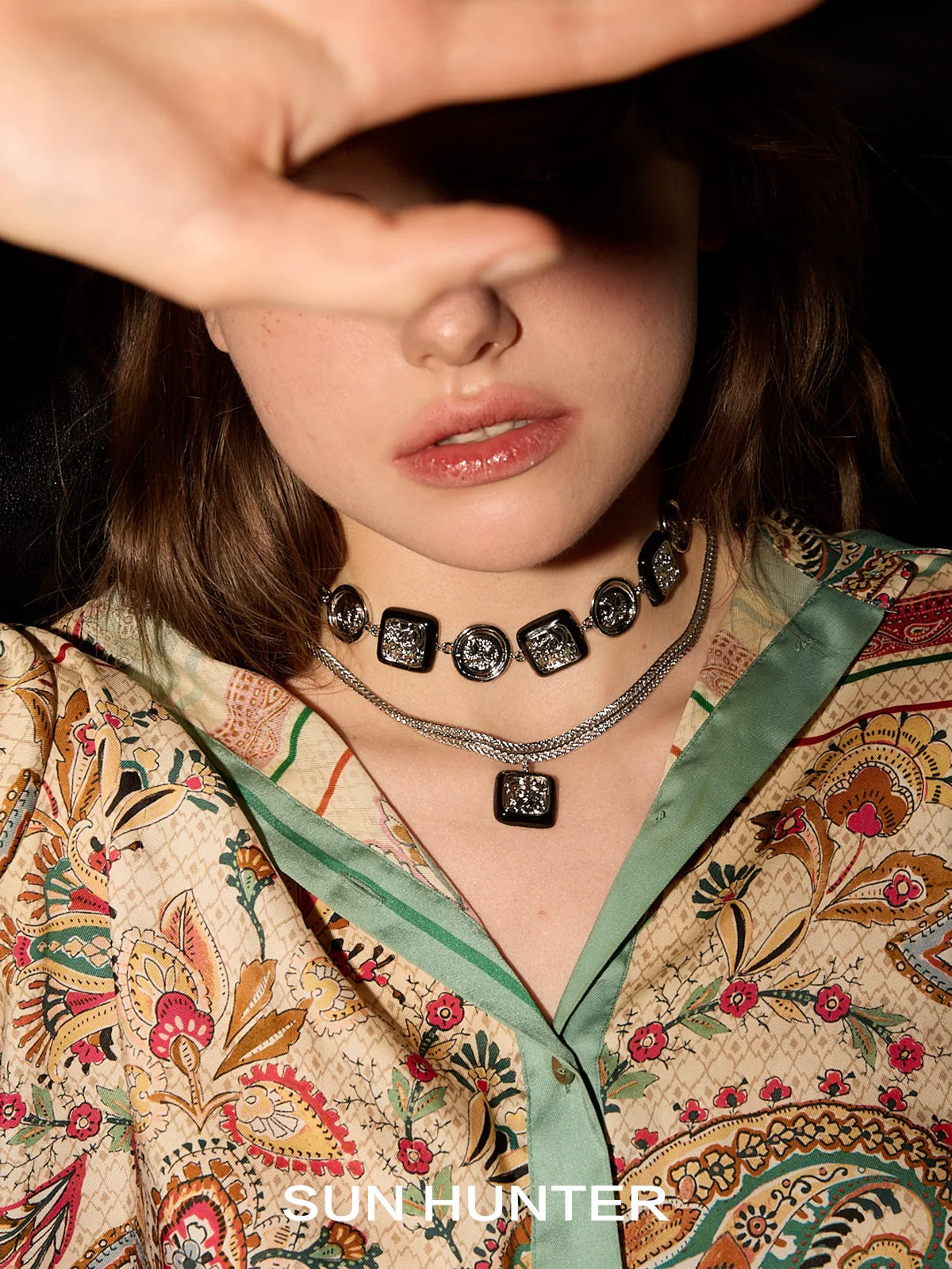 Model wearing vintage coin earrings and layered necklaces with intricate designs from SUN HUNTER