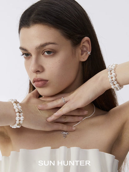 Model wearing a vintage cross pearl bracelet alongside other elegant jewelry pieces