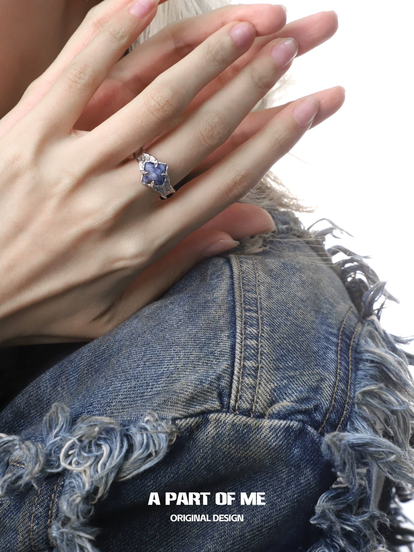 Elegant violet gemstone ring set in silver worn on a hand with a stylish denim jacket