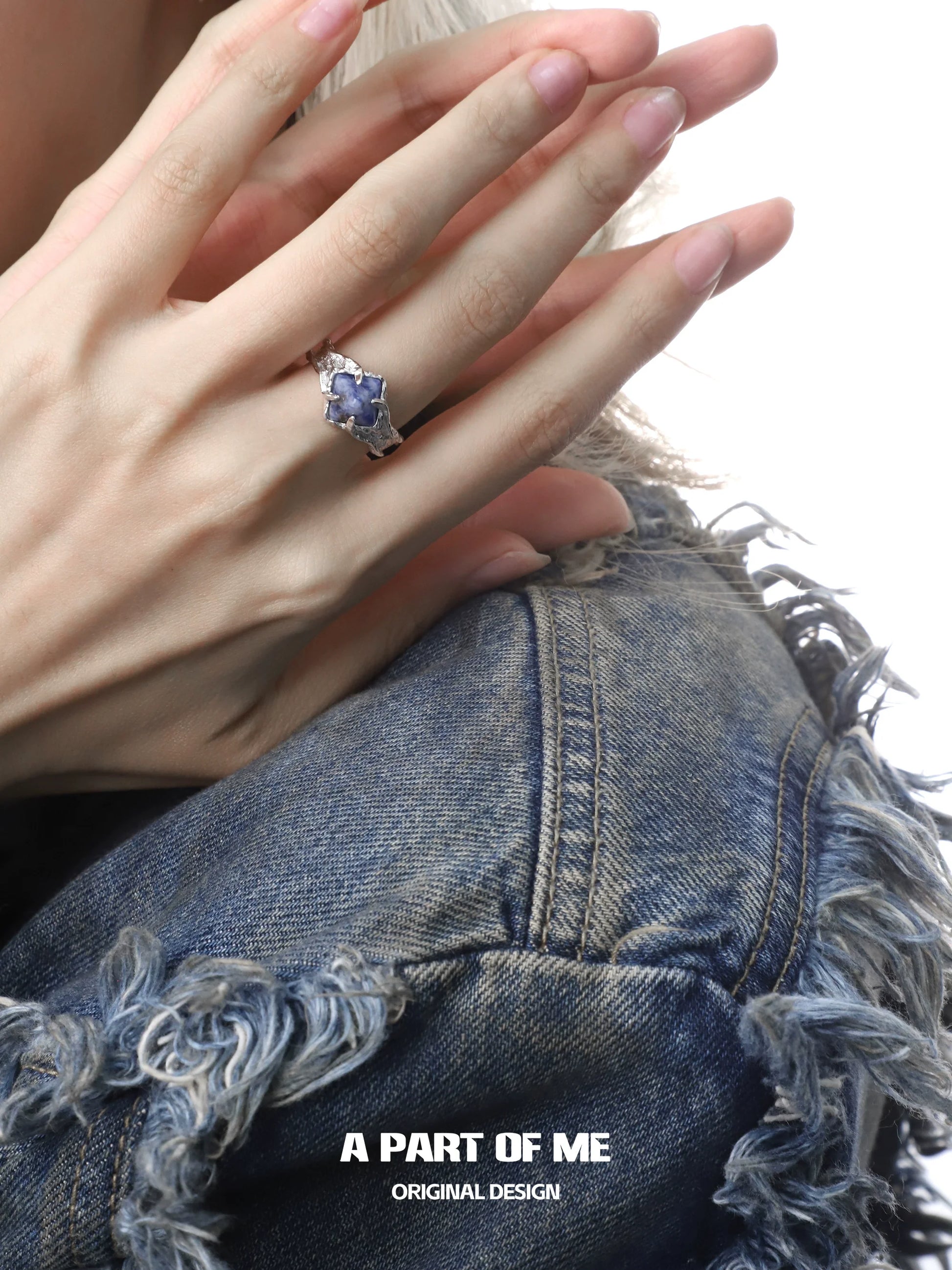 Elegant violet gemstone ring set in silver worn on a hand with a stylish denim jacket