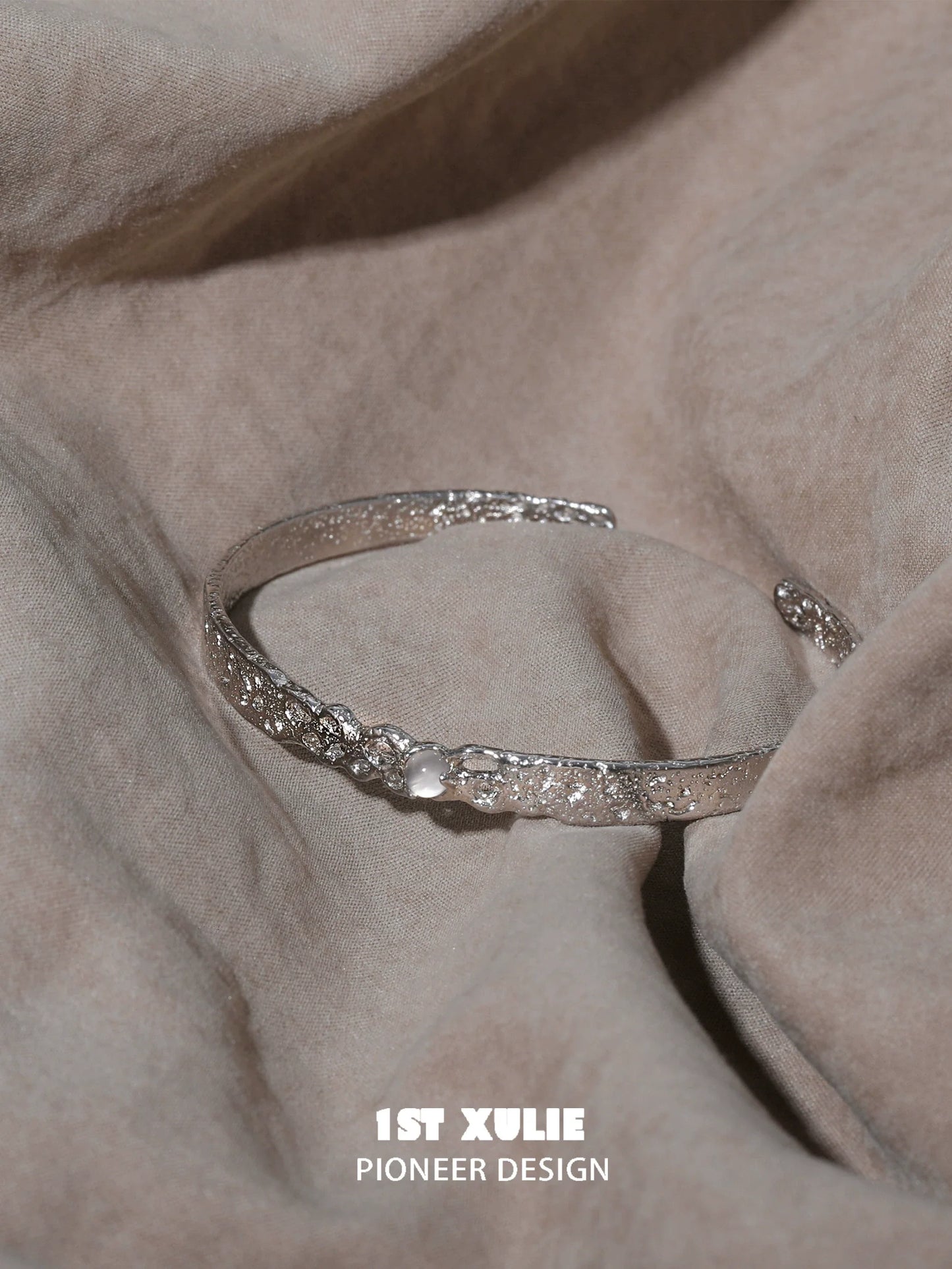 Elegant white agate bangle bracelet on a soft fabric background, showcasing intricate details