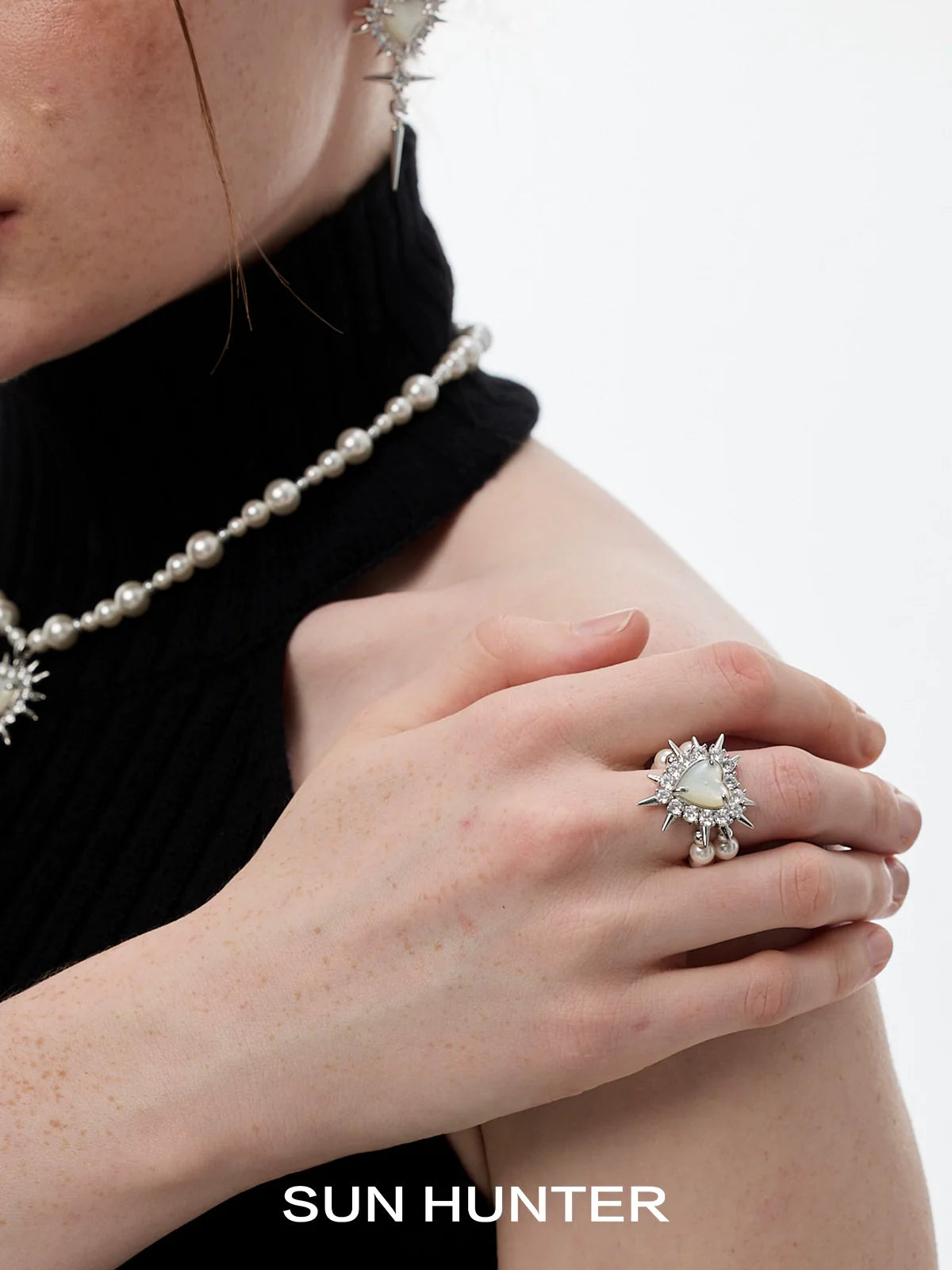 Close-up of a hand wearing a SUN HUNTER Y2K pearl rivet ring with decorative details